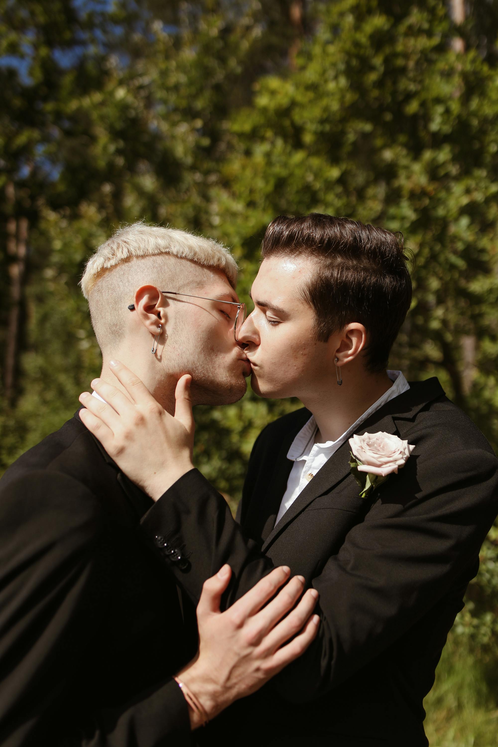 men in black suits kissing under tree