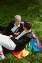 Man in Black Suit Jacket Sitting Beside Boy in White Pants on Green Grass