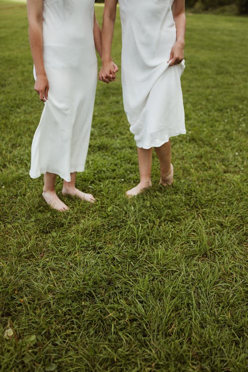 Women in White Dress Standing Barefeeet on Green Grass Field