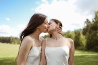 两个女人在阳光明媚的户外亲吻拥抱，表达爱意
