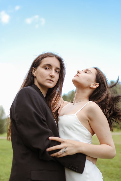 A Couple Embracing while Standing on Green Grass Field