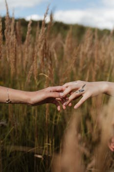 在晴朗的天空下，两只手轻轻抚摸着宁静的麦田