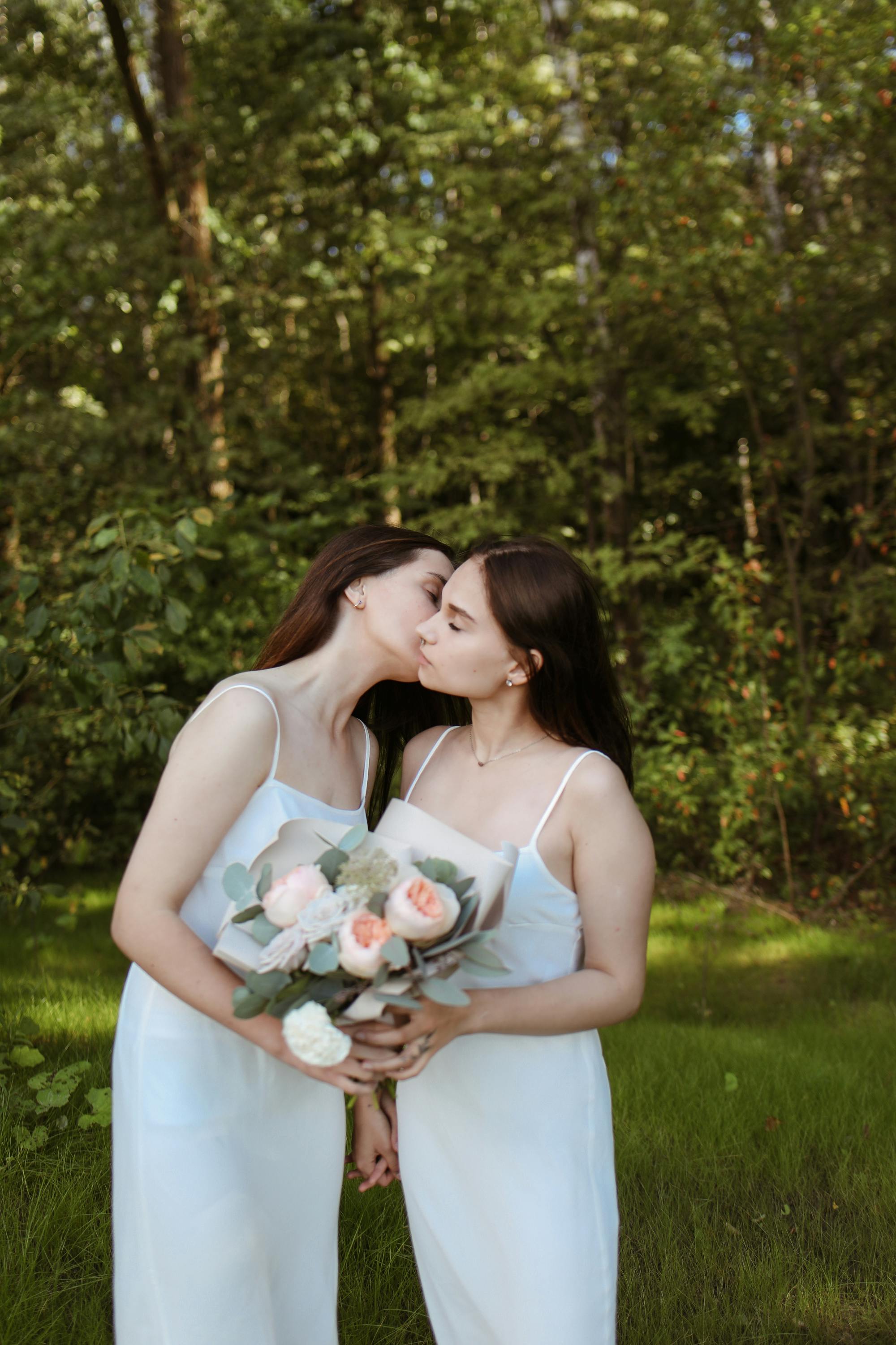 a couple in white dress kissing in the park