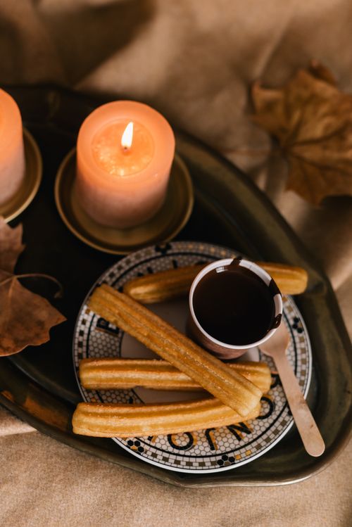 Free A warm display of churros with chocolate beside glowing candles, perfect for cozy evenings. Stock Photo