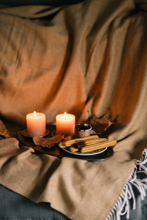 Free Warm autumn scene with lit candles and churros on a blanket, creating a cozy atmosphere. Stock Photo