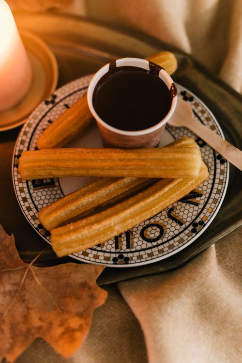 Free Churros served with chocolate sauce on a decorative plate, captured in a cozy setting. Stock Photo