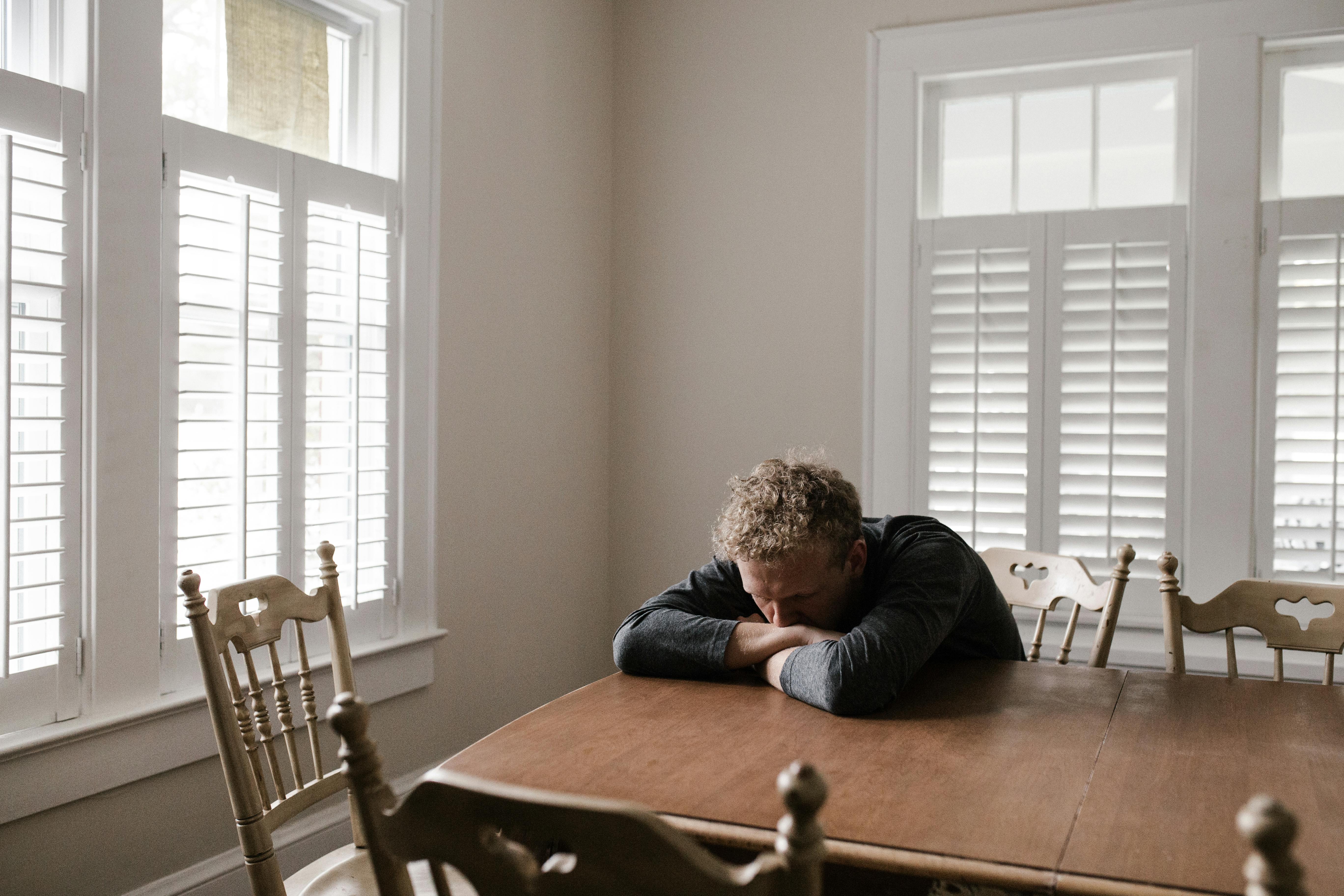 Free Man in Gray Long Sleeve Shirt Sitting on Brown Wooden Chair Stock Photo