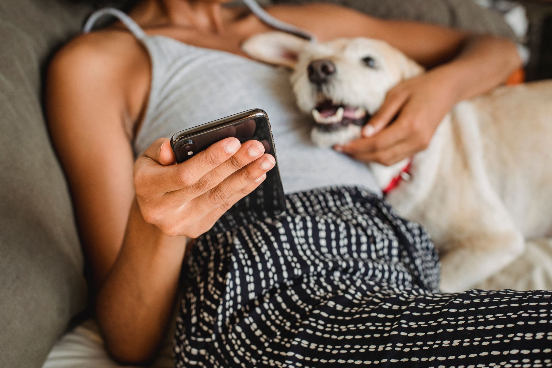Pet parent using a smartphone while relaxing with a dog