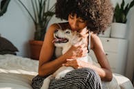 一位卷发女子在室内舒适的床上，深情地拥抱着她快乐的狗