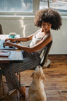 年轻女子在家带着狗用笔记本电脑工作，体现了现代自由职业者的生活方式