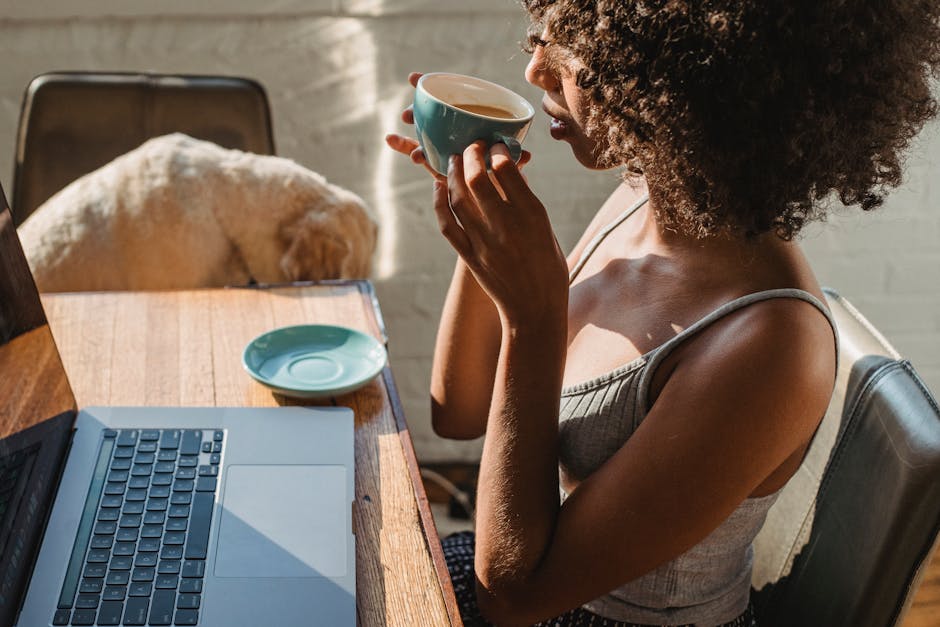 Does Pet Insurance Actually Save You Money? A woman enjoys coffee while working on a laptop at home with her dog nearby.