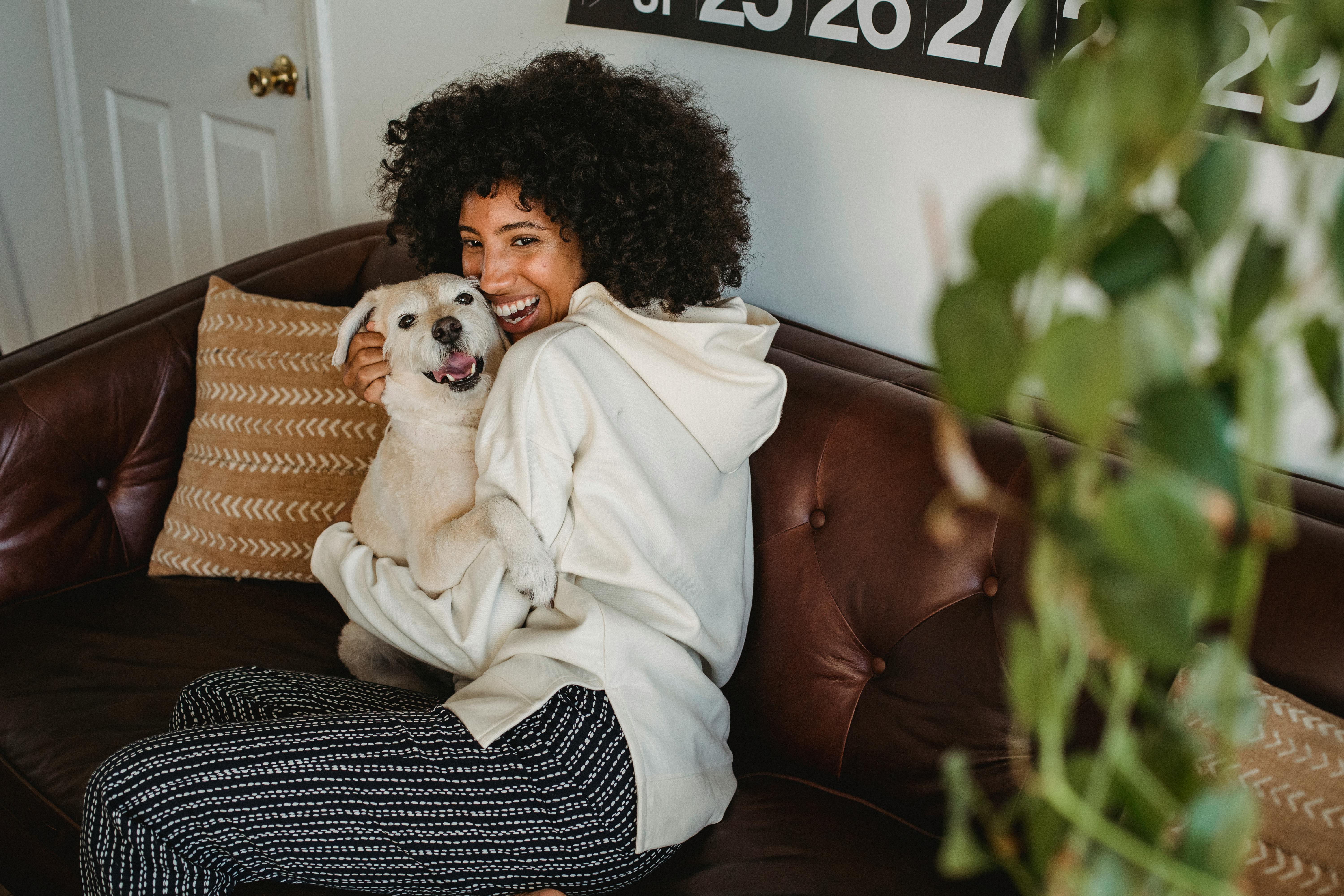 smiling african american lady cuddling with dog in living room