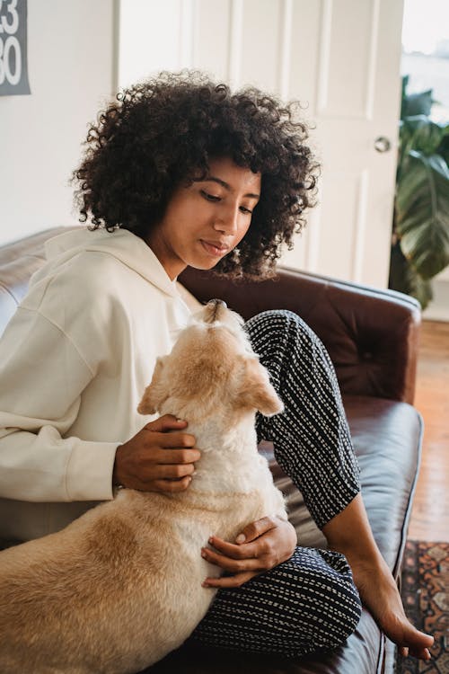 Black female hugging with dog in living room