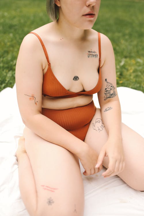 Free Tattooed Woman Kneeling on White Blanket Stock Photo