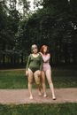 两名妇女身着紧身衣，赤脚站在郁郁葱葱的绿色公园里