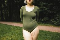 Woman in Green Long Sleeve Shirt Standing on Green Grass Field