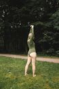 Woman in Green Long Sleeve Shirt and Gray Shorts Standing on Green Grass Field
