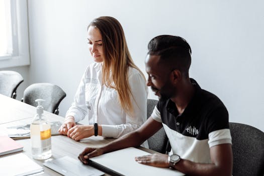 Two colleagues collaborating in a modern office setting, promoting teamwork and diversity.