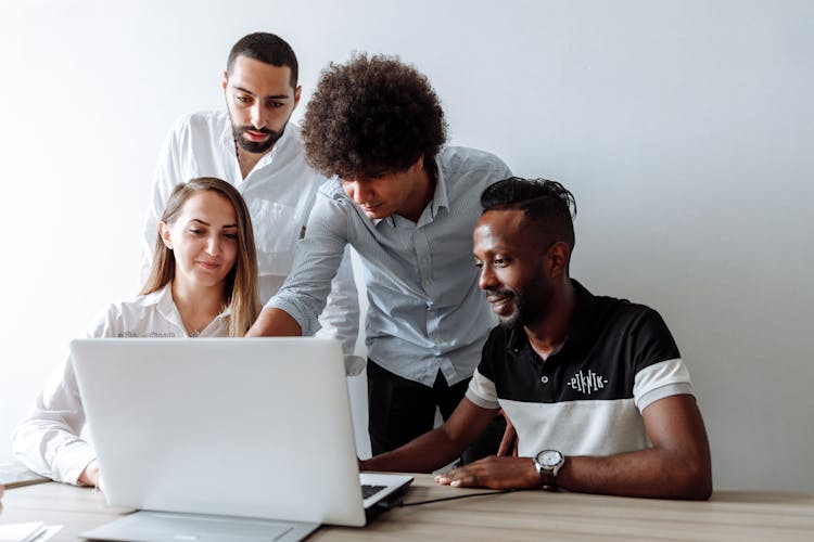 A Group Of People Having A Discussion While Looking At Laptop