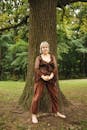 Woman in Black and Red Dress Standing Beside Brown Tree
