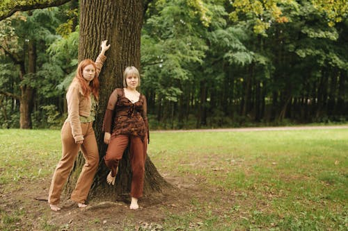 Women Standing Barefooted while Leaning on the Tree