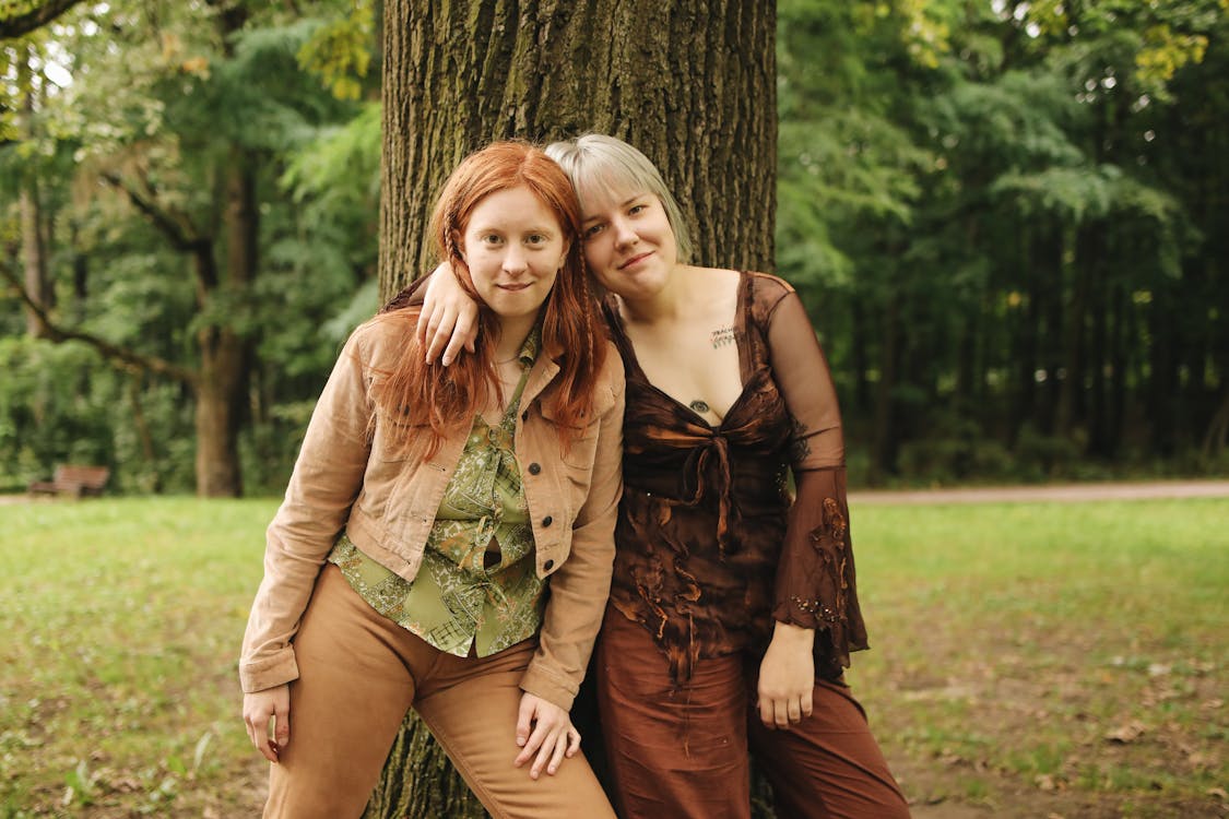 Two friends embracing by a tree.