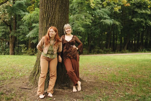 Smiling Women Leaning on Tree Trunk