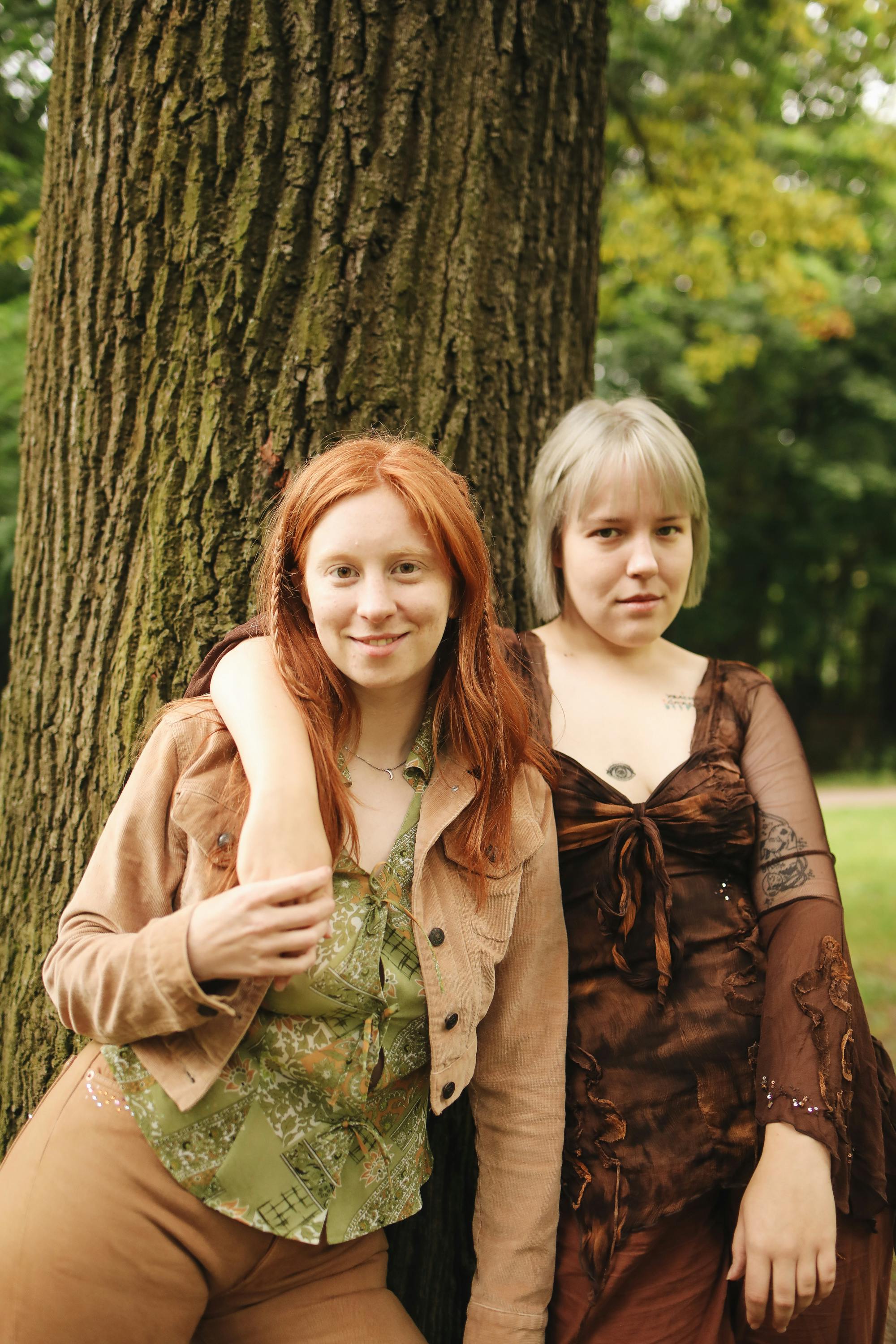 women posing in front of a tree trunk