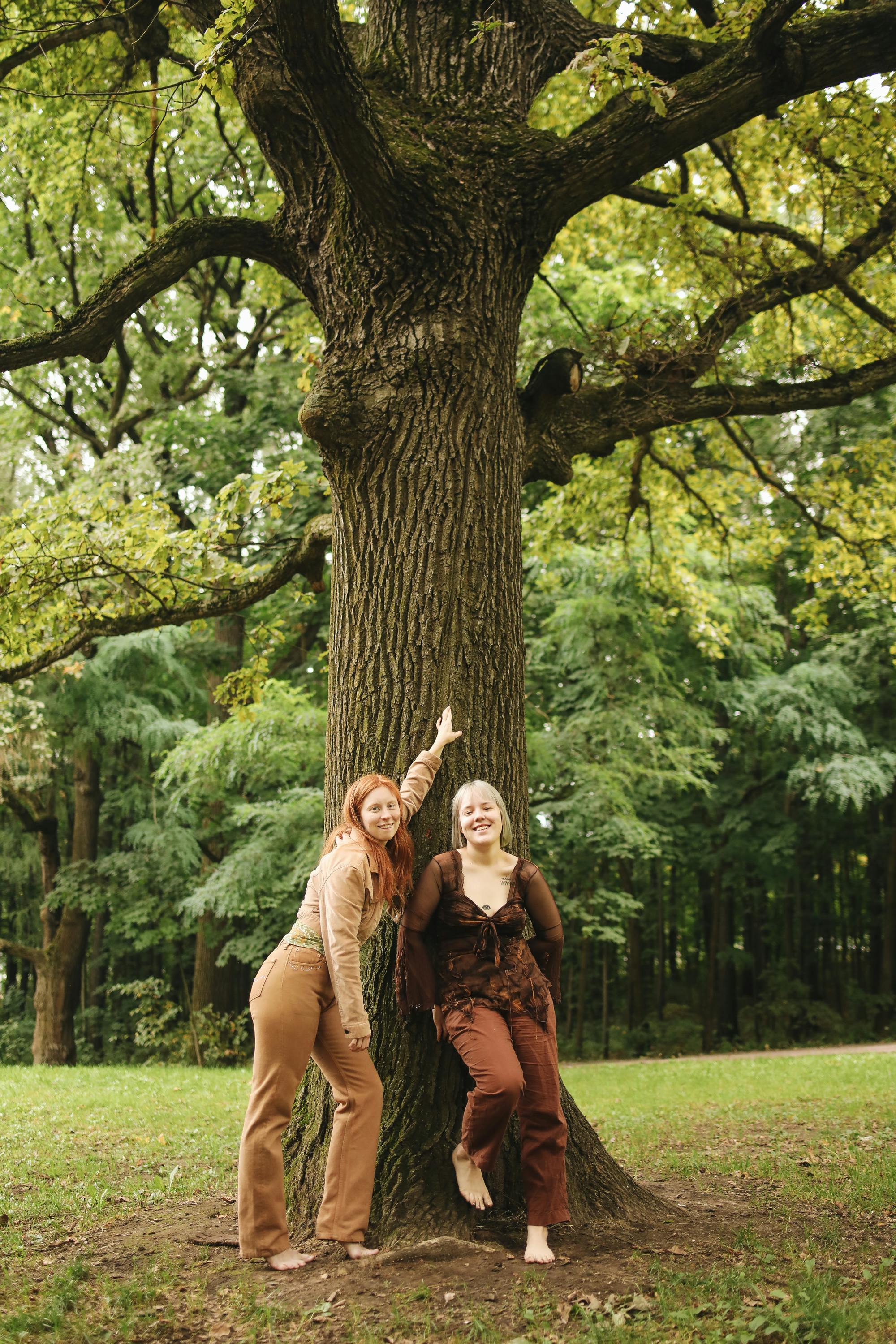 smiling women leaning on a tree trunk