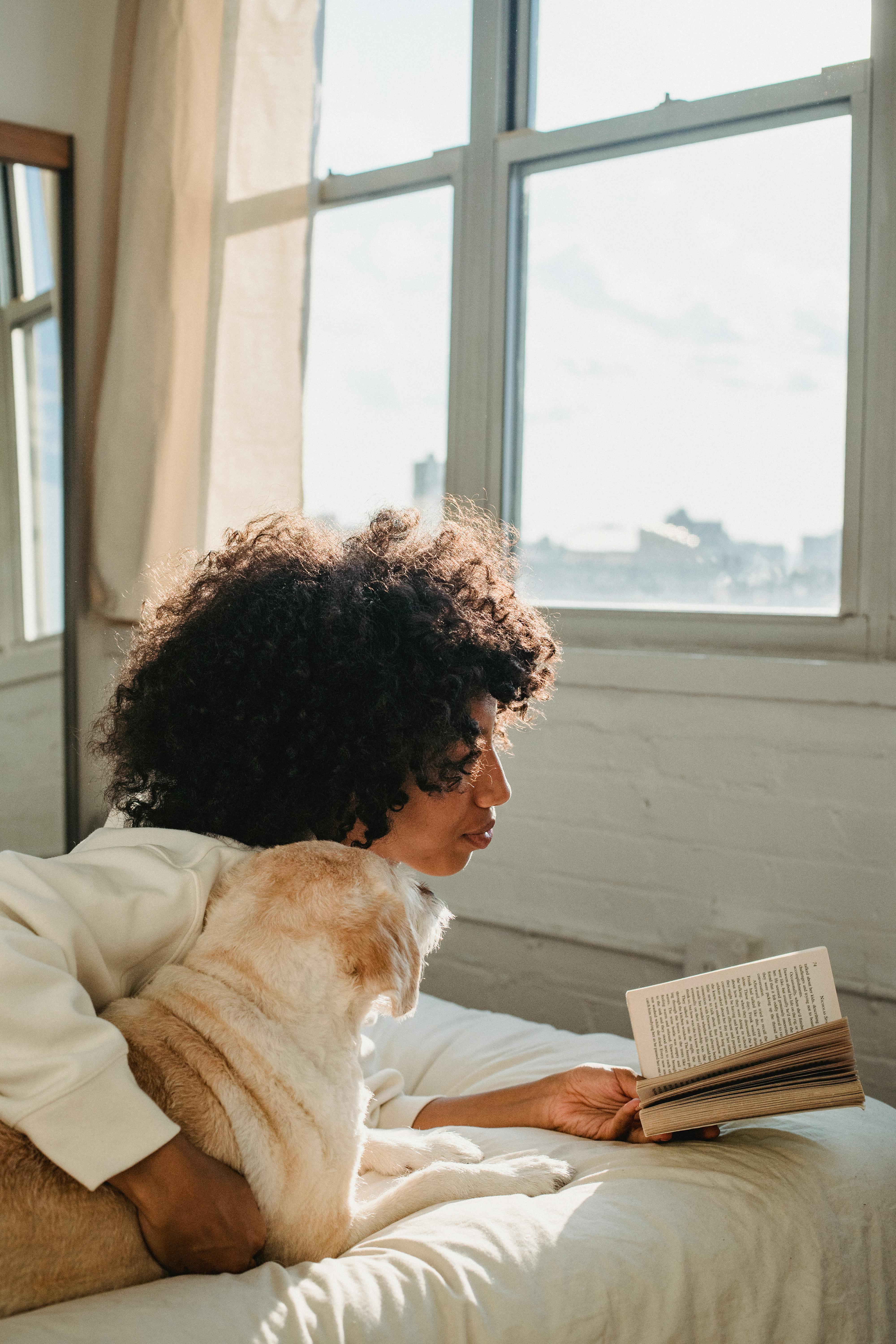 black woman embracing dog while reading