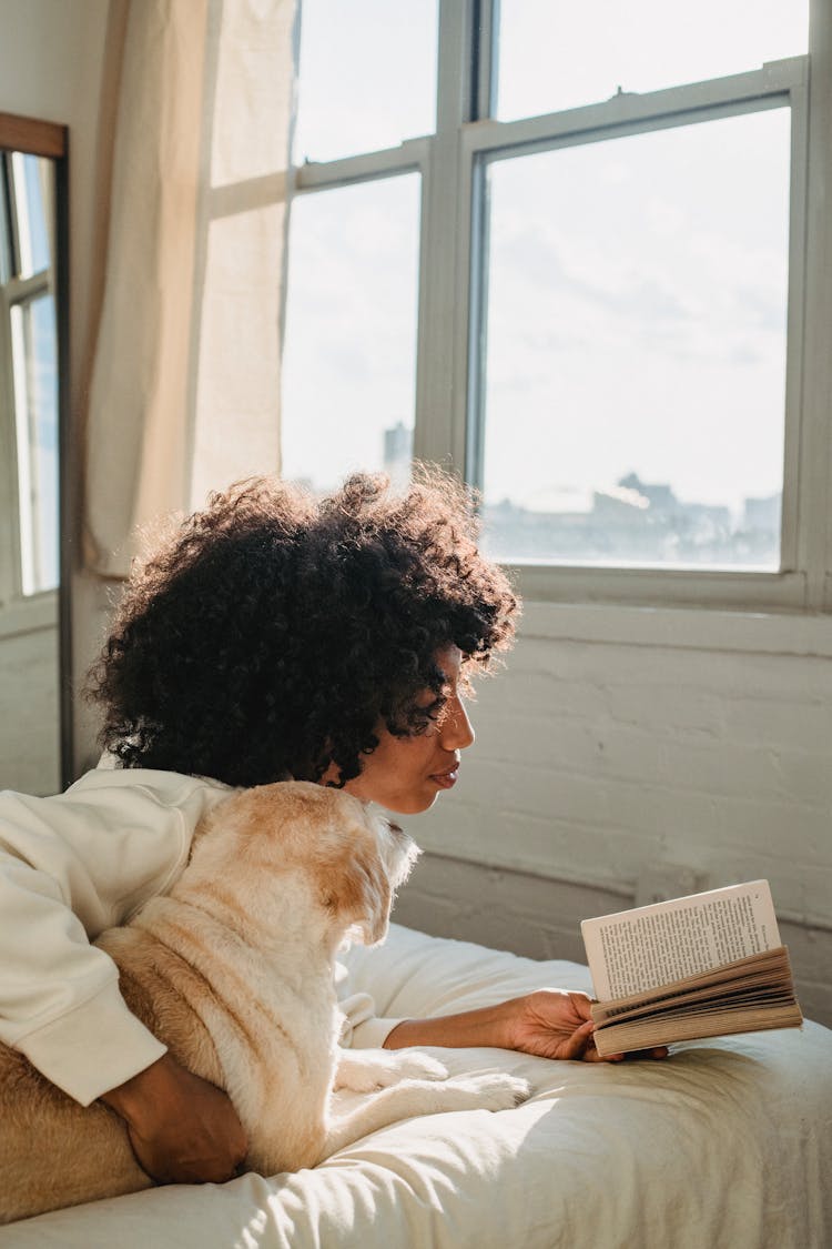 Black Woman Embracing Dog While Reading