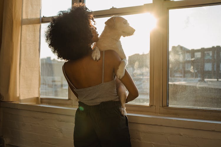 Black Woman Holding Dog Near Window