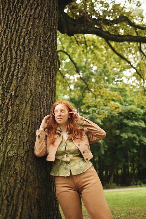 A Woman in Brown Jacket Leaning on the Tree Trunk
