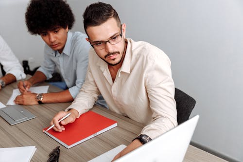 Man Wearing Beige Dress Shirt Looking at a Laptop