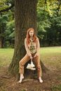 Woman in White Long Sleeve Dress Sitting on Tree Trunk