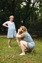 Woman in White Tank Top and Blue Denim Shorts Carrying Girl in White Dress on Green