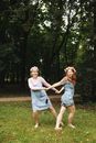 Woman in Blue Denim Dress Holding Girl in White Dress on Green Grass Field