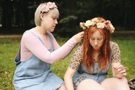 Girl in Blue Dress Sitting on Girl in White Tank Top