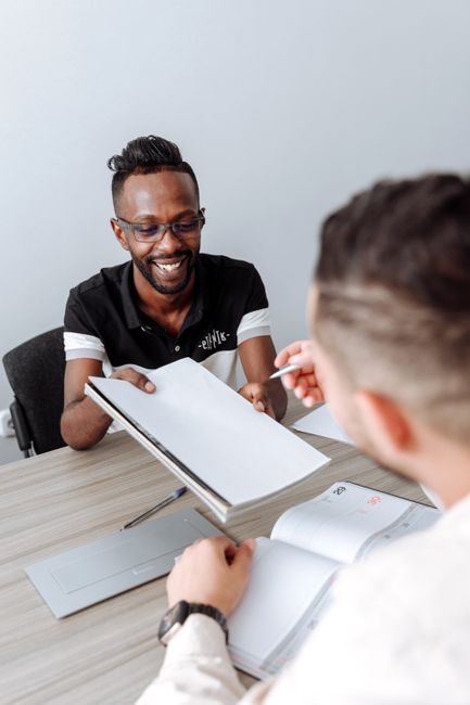Two colleagues engage in a discussion during an office meeting, sharing documents and ideas. Two colleagues engage in a discussion during an office meeting, sharing documents and ideas.