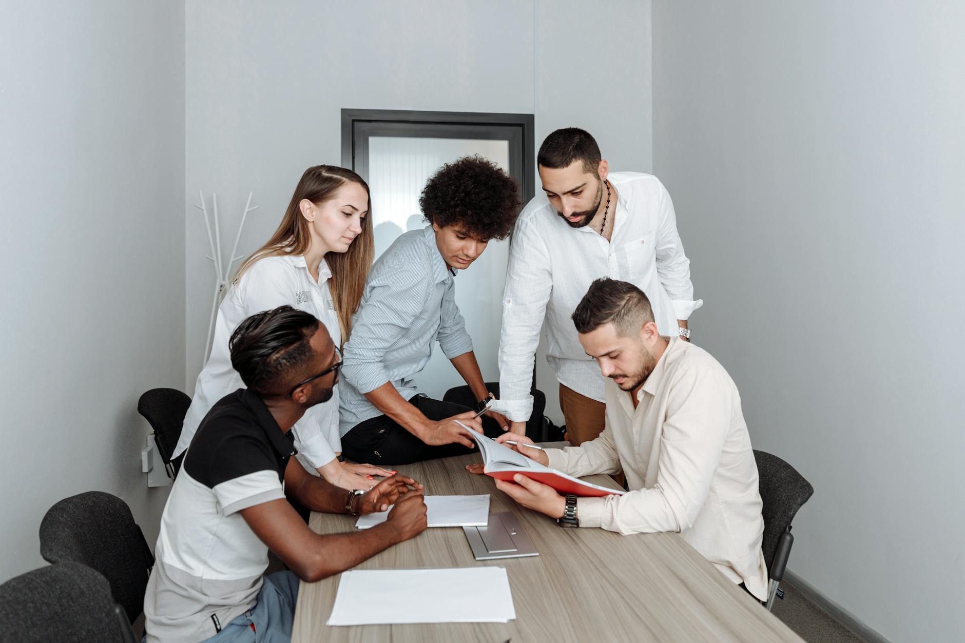 A diverse team of young professionals collaborating during a business meeting in a modern office setting.