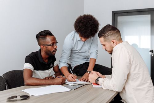 Free Three diverse men engaged in a business meeting, planning and writing in an office. Stock Photo