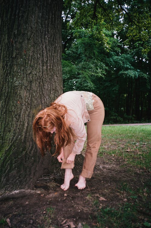 A Woman in Pink Jacket and Brown Pants Standing Beside the Tree