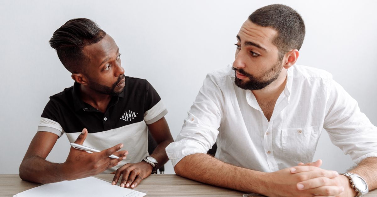 Two diverse men engage in a serious office discussion, emphasizing collaboration and teamwork.
