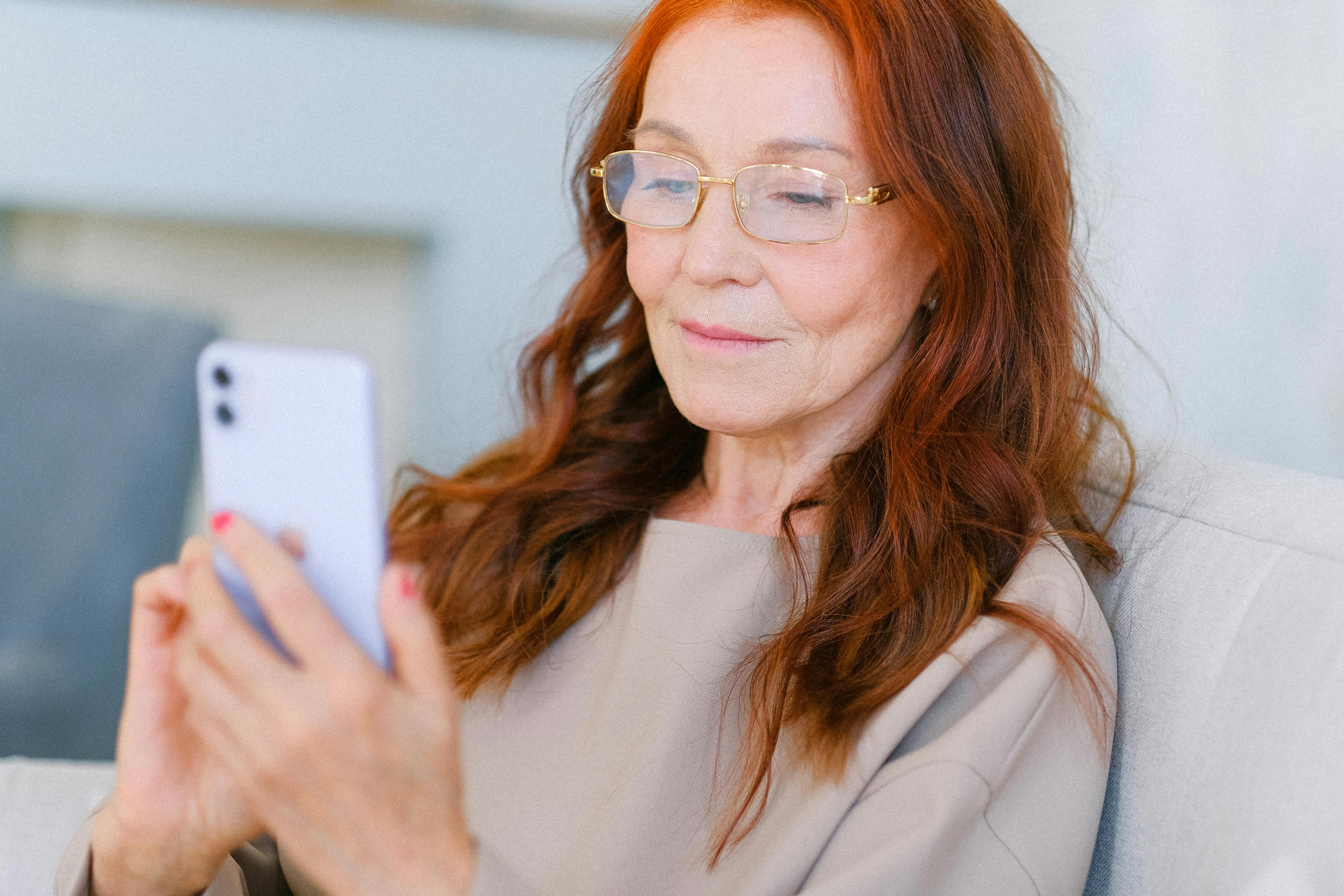 elderly woman with red hair in eyeglasses making video call