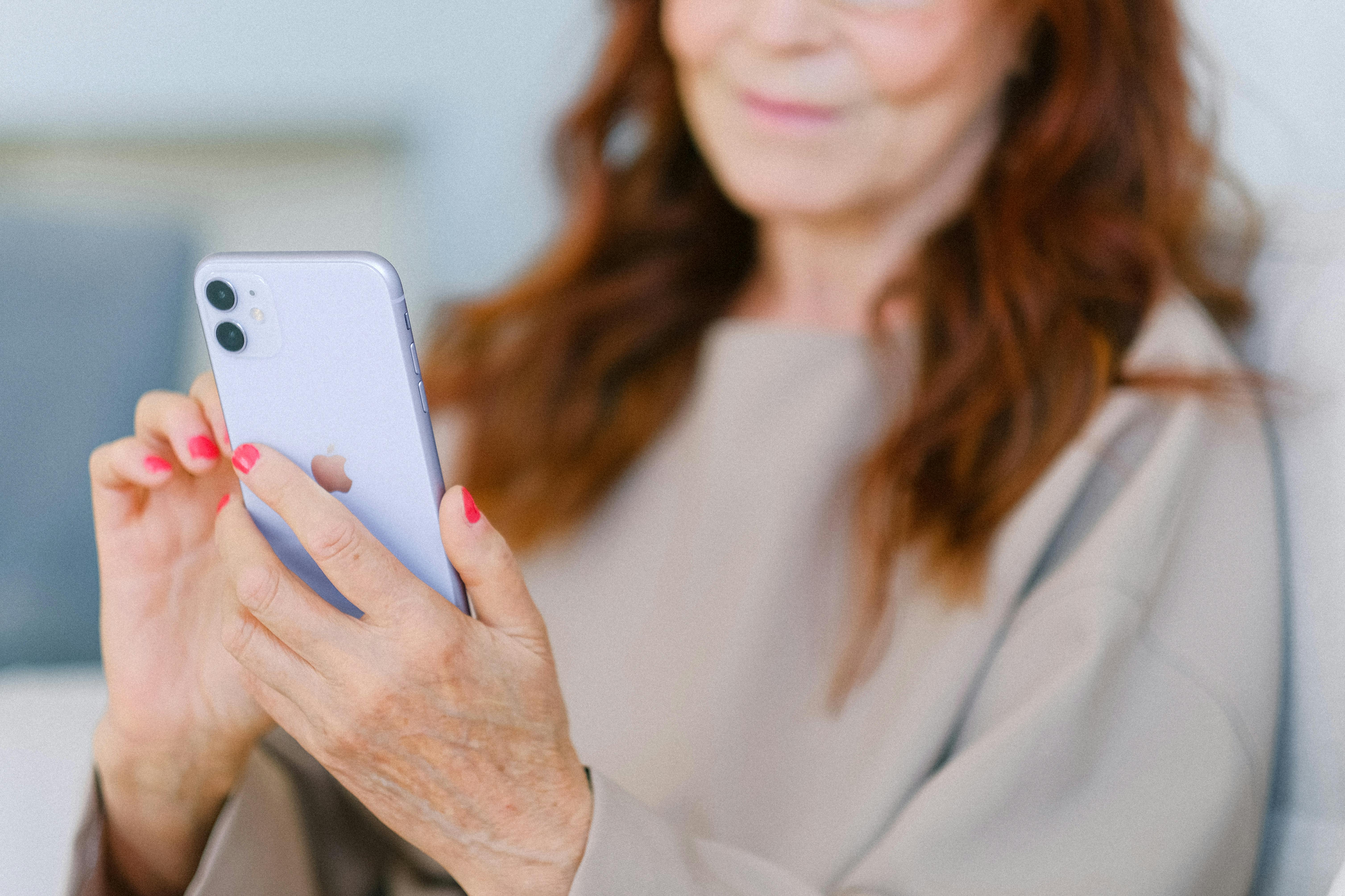 senior woman with red hair using contemporary smartphone