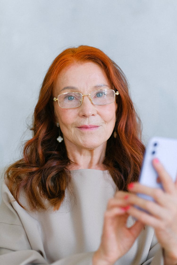 Portrait Of Middle-aged Woman In Glasses Using Cell