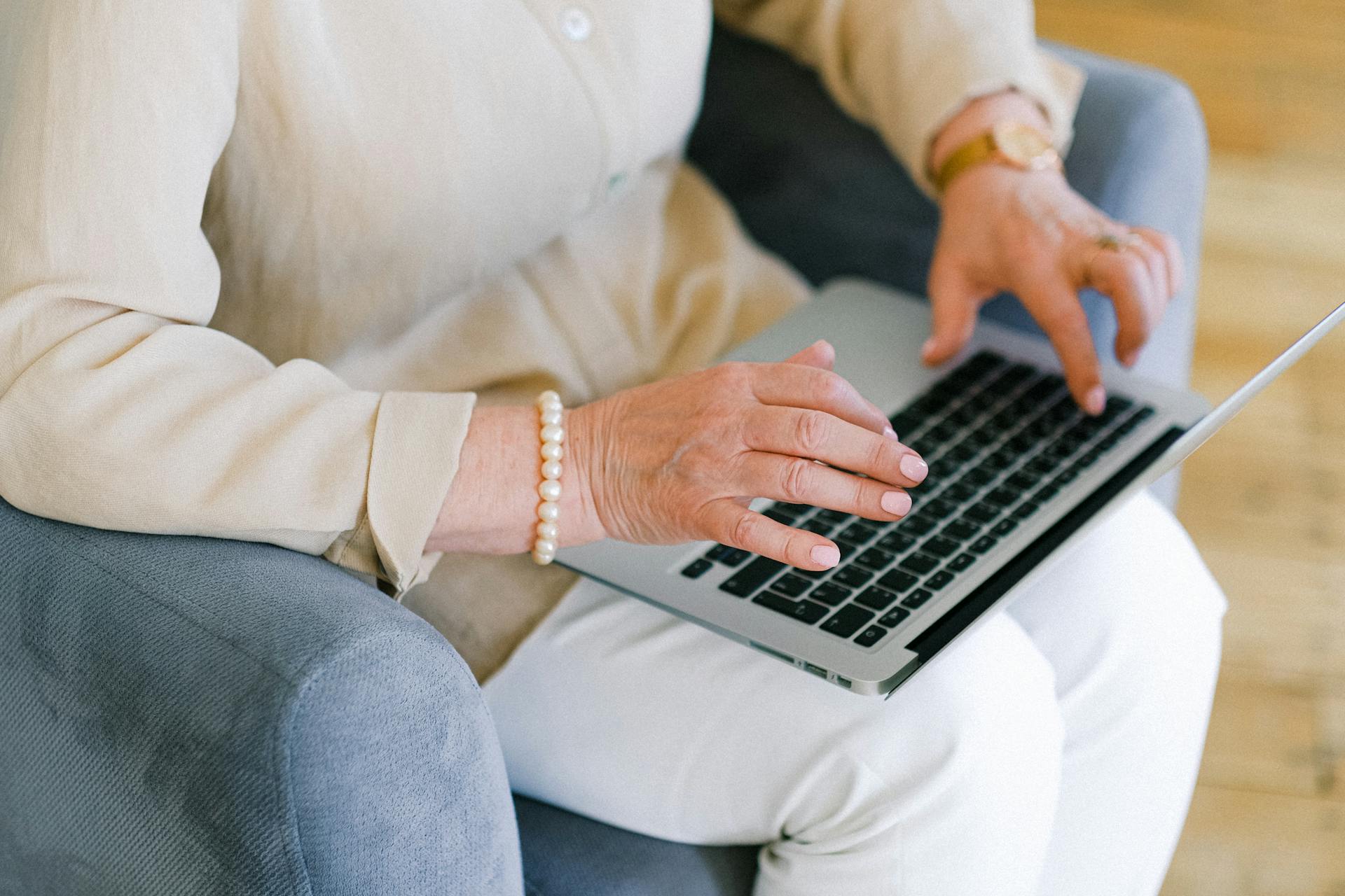 Een oudere vrouw typt een belangrijk rapport op het toetsenbord van een laptop