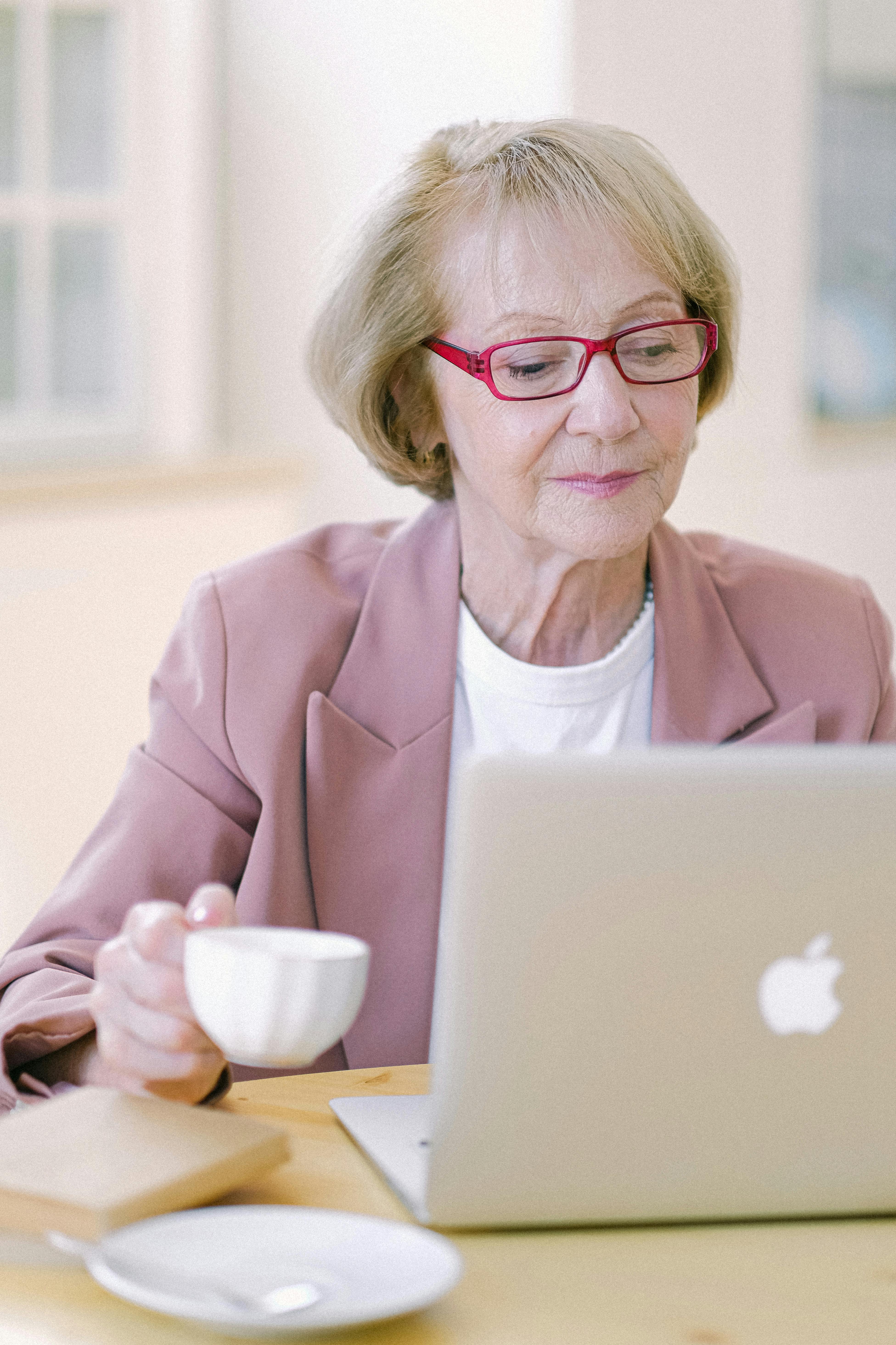 elderly businesswoman with mug using laptop