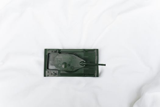 Green toy tank viewed from above on a white surface, emphasizing playtime and imagination.