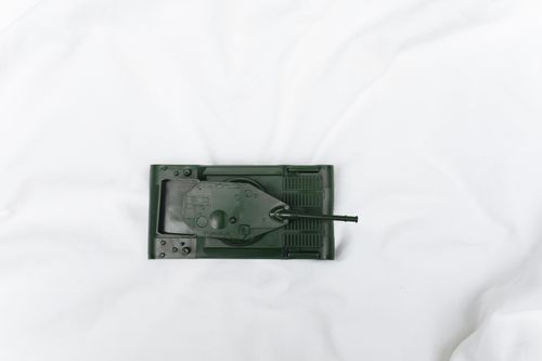 Free Green toy tank viewed from above on a white surface, emphasizing playtime and imagination. Stock Photo